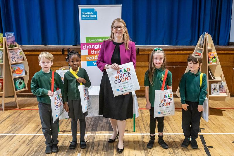 Shirley-Anne Somerville standing with Liberton Primary School pupils holding their new Read, Write, Count bags